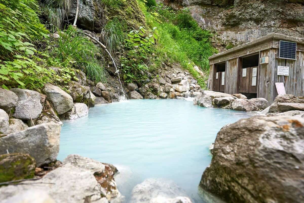Outdoor onsen surrounded by green mountains in Myoko