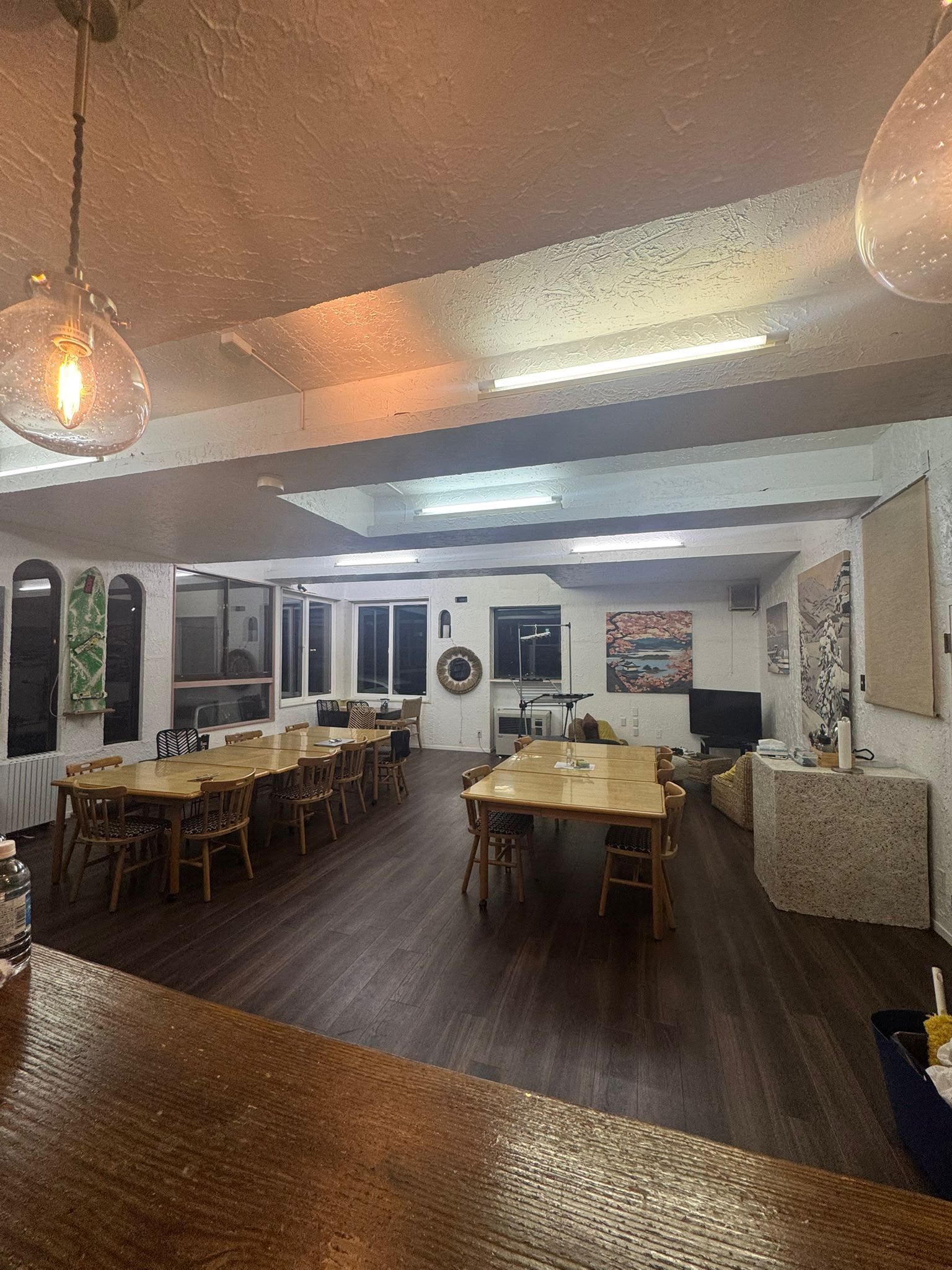 Open dining hall with amber pendant lights and wooden tables