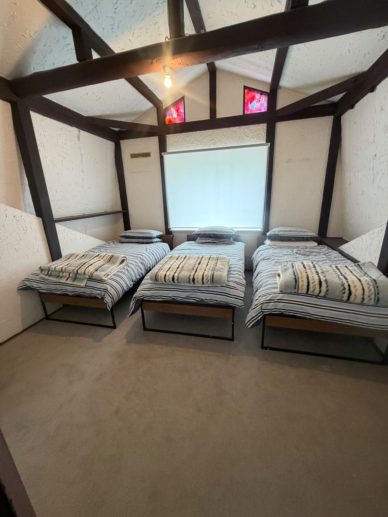 Bedroom with three single beds, striped bedding, and exposed beams