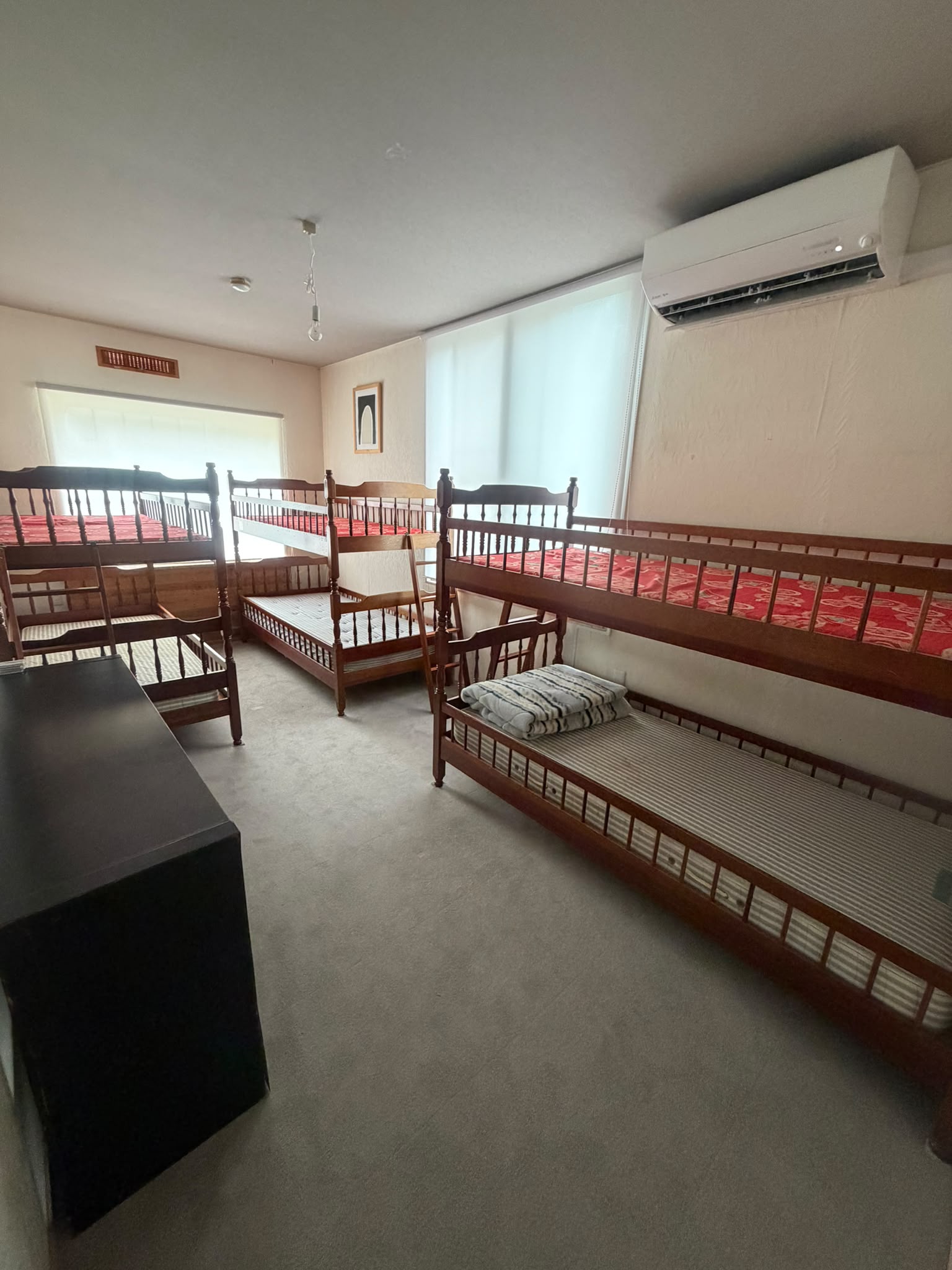 Shared bunk room with wooden beds and large windows